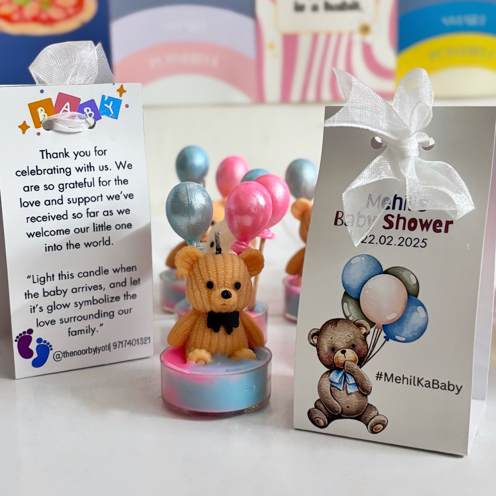 Baby shower candle with teddy bear design and decorative cards on a white surface.