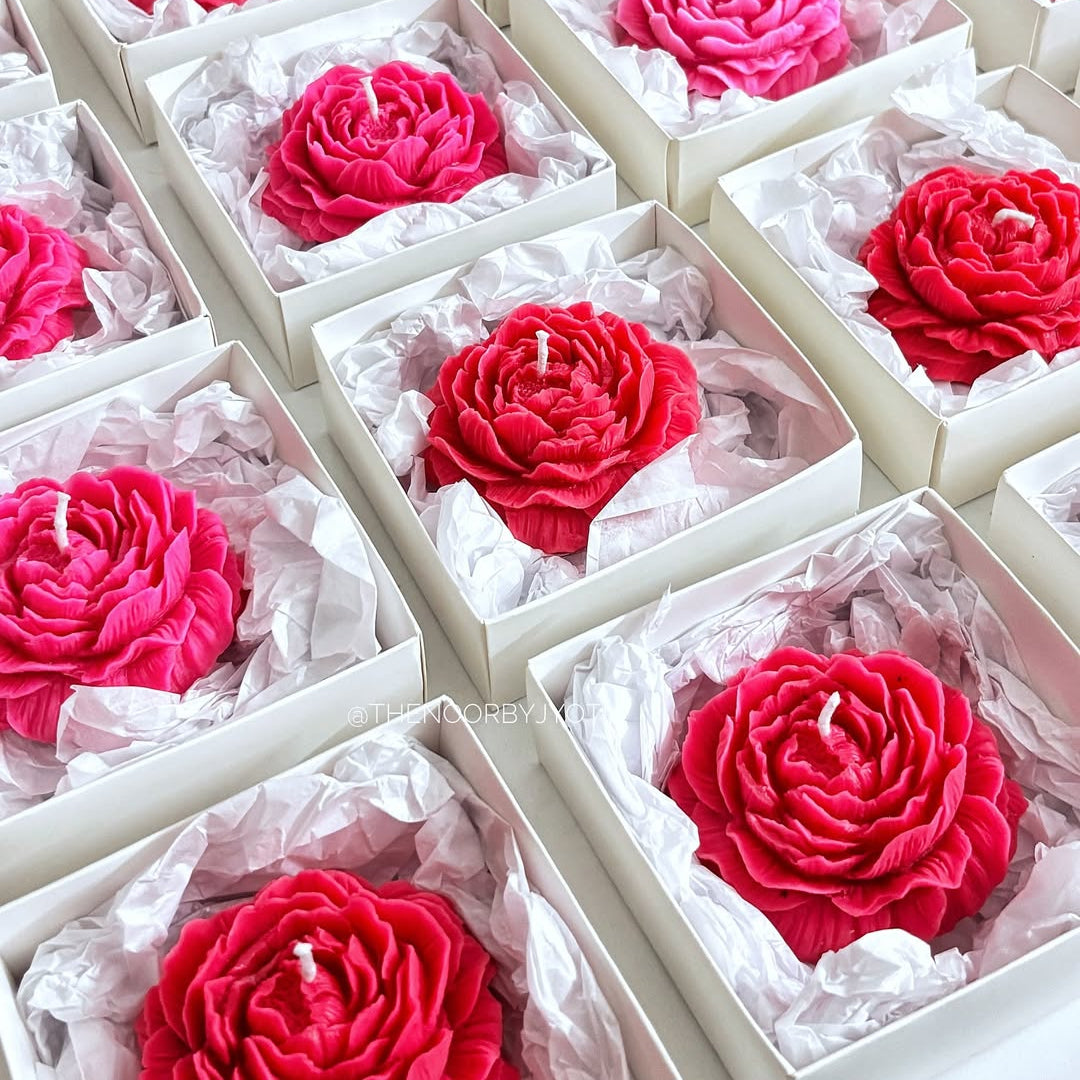 Red and pink rose-shaped candles in white boxes arranged in a grid.