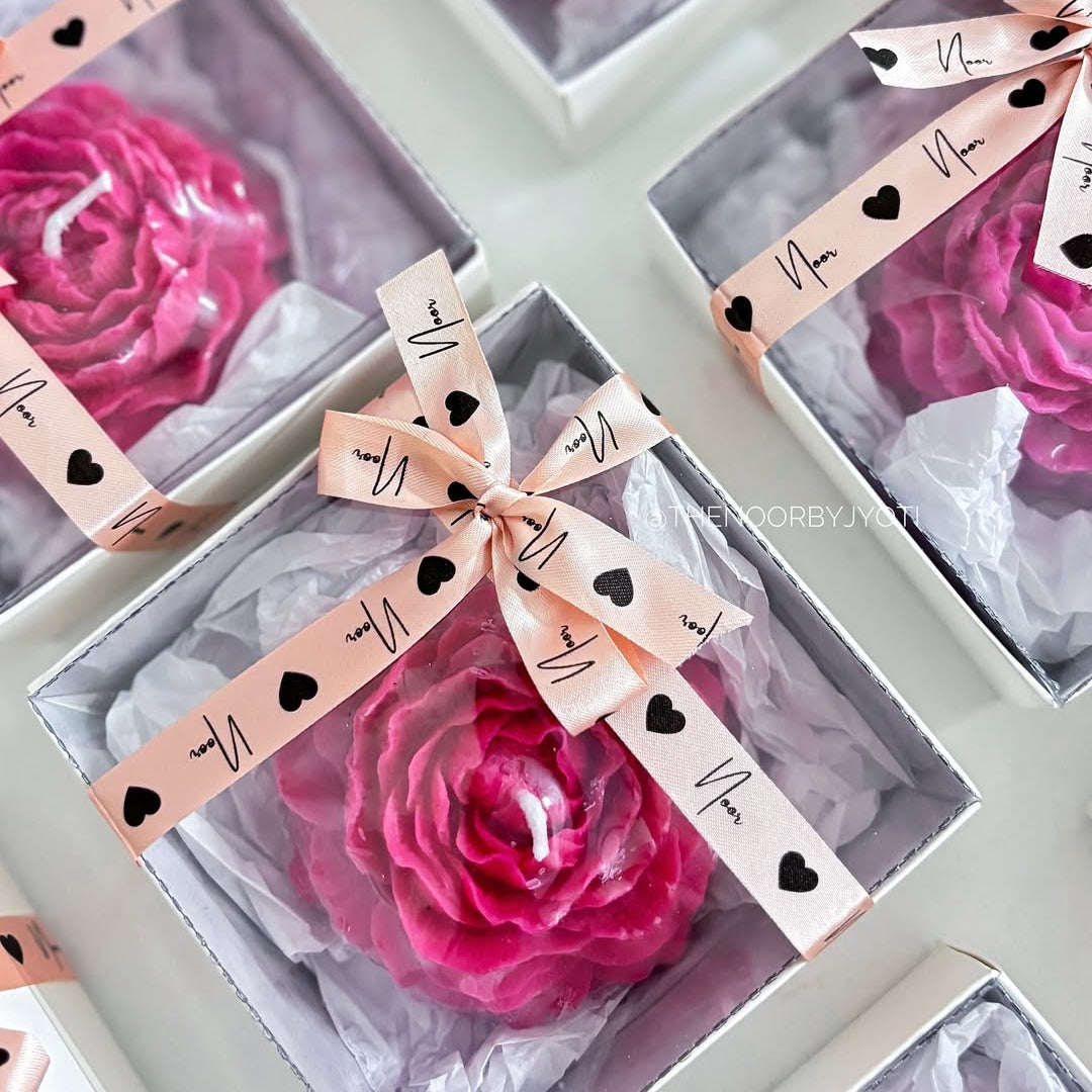 Pink roses in clear boxes with decorative ribbons and heart labels.